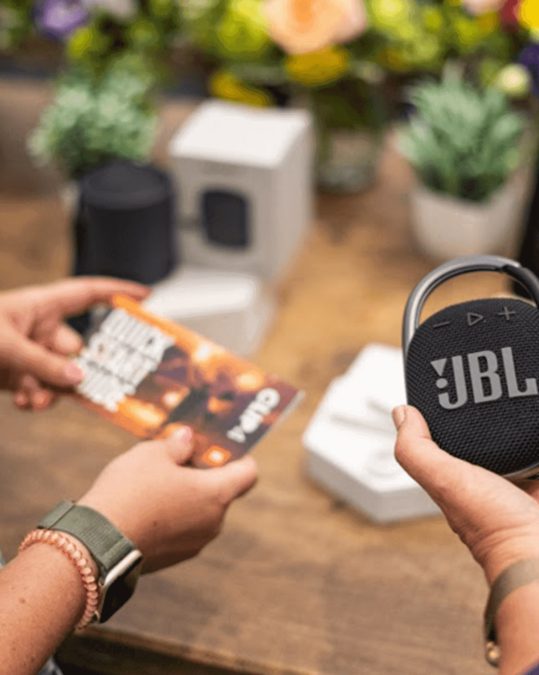 two people holding a compact speaker and portable charger in their hands