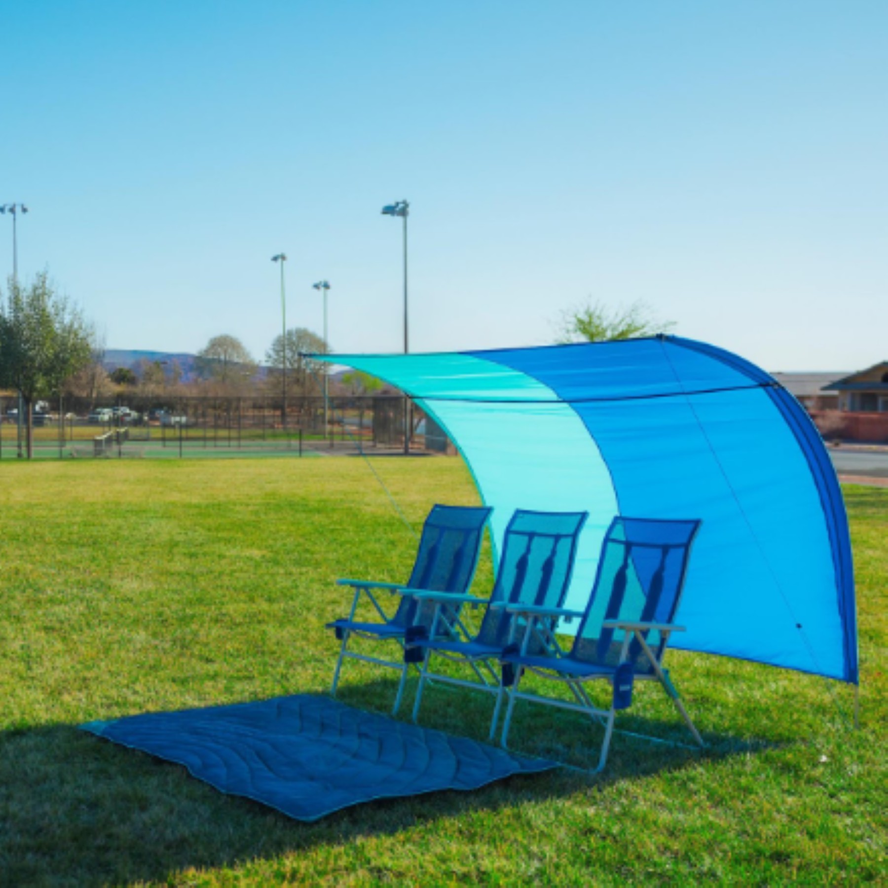 Branded Shibumi Park Vista shade set up at park sideline with chairs