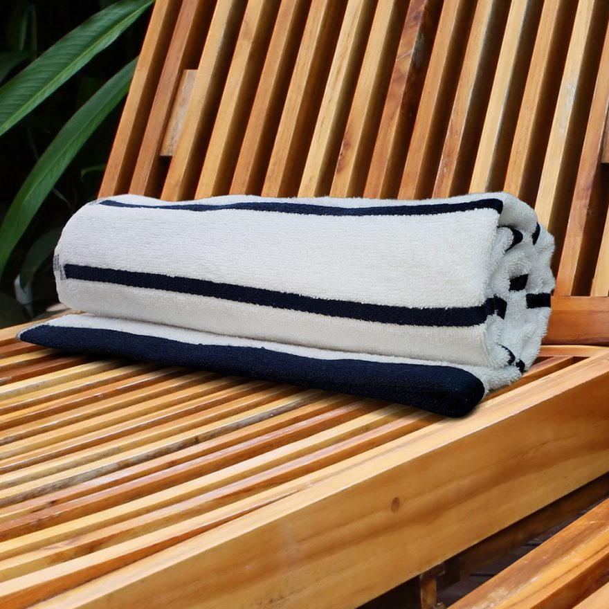 rolled custom branded pool towels in navy and white stripe on wooden lounge surface
