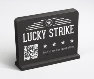 Black tabletop QR code counter sign with a scan to see our latest offers message