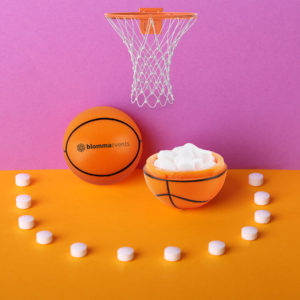 Orange and black basketball-shaped mint container with basketball hoop backdrop