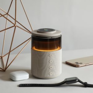 Collective 5-in-1 wireless speaker and charger glowing on a styled desk