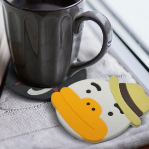 Custom shaped PVC coaster molded as a cartoon duck in a hat, under a black coffee mug