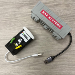Custom molded PVC 3 port USB hubs shaped like branded equipment boxes on a wood desk